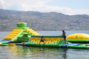 a green inflatable on a body of water with a mountain in the background